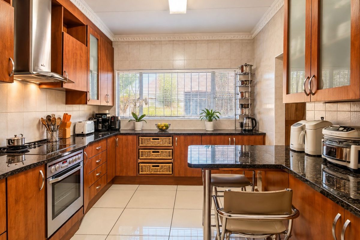 A well-maintained kitchen featuring warm wooden cabinetry, granite countertops, a breakfast nook, and modern stainless steel appliances.