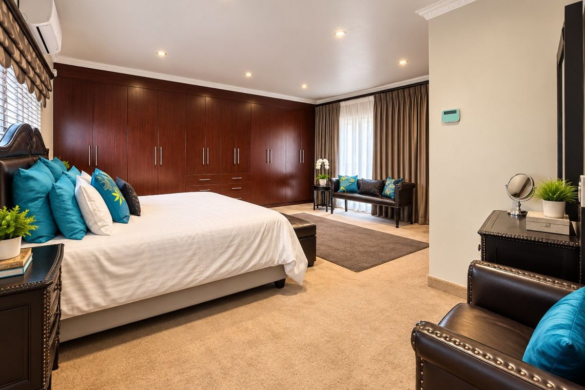 Spacious bedroom featuring extensive dark wood built-in cupboards, recessed lighting, air conditioning, and neutral carpeting.
