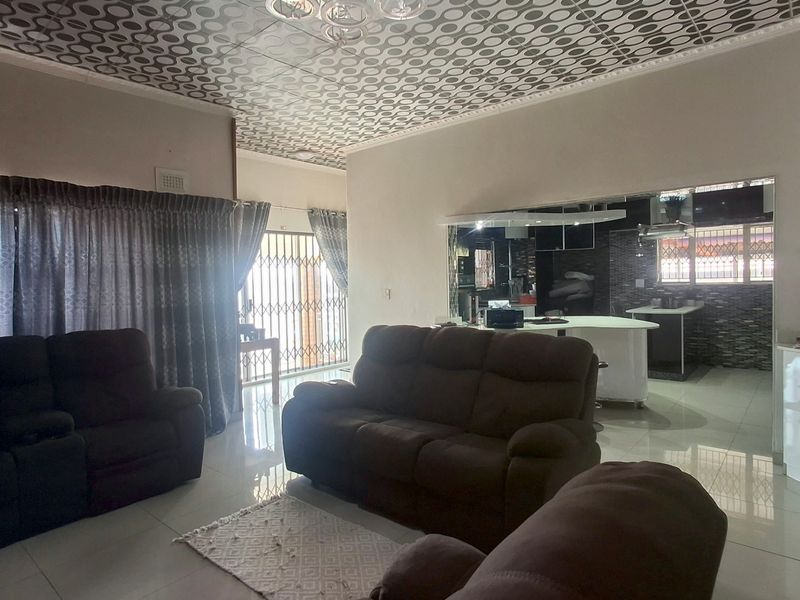 Spacious open-plan living area featuring tiled flooring, decorative ceiling tiles, and a modern kitchen island with integrated cabinetry.