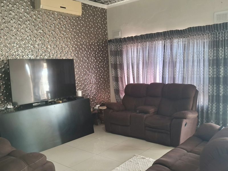 A living room featuring tiled flooring, a split-system air conditioner, and decorative wall cladding.