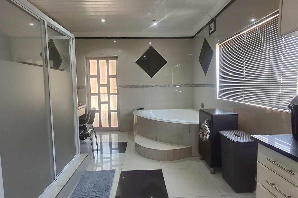 Spacious bathroom featuring a corner bathtub, separate shower enclosure, tiled finishes, and built-in vanity cabinetry with modern lighting.
