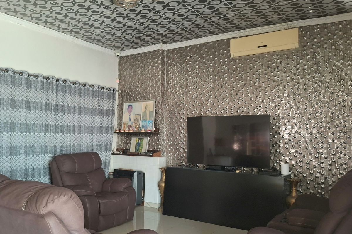 Living room featuring tiled flooring, decorative ceiling tiles, and a split-system air conditioner, with dated wall finishes throughout.