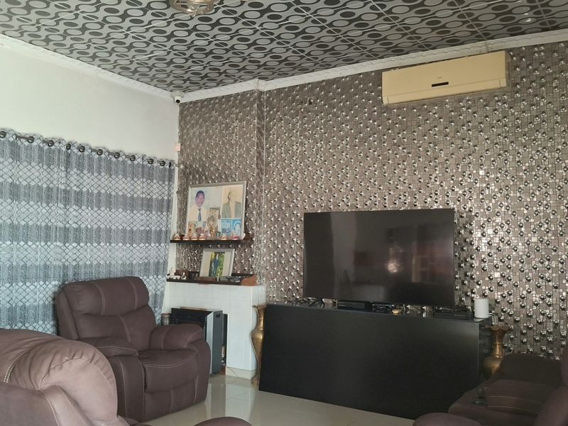 Living room featuring tiled flooring, decorative ceiling tiles, and a split-system air conditioner, with dated wall finishes throughout.
