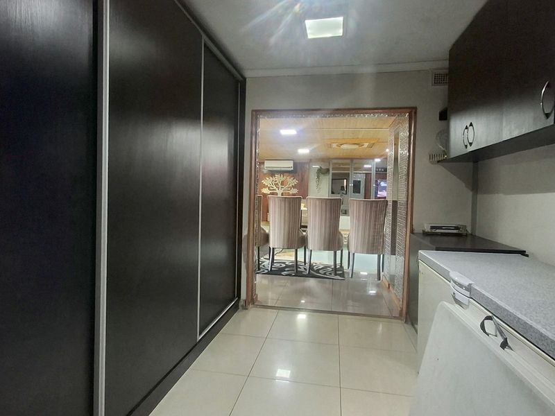 A functional scullery area featuring extensive built-in cabinetry and tiled flooring, providing a transition space between the kitchen and the adjacent living area.