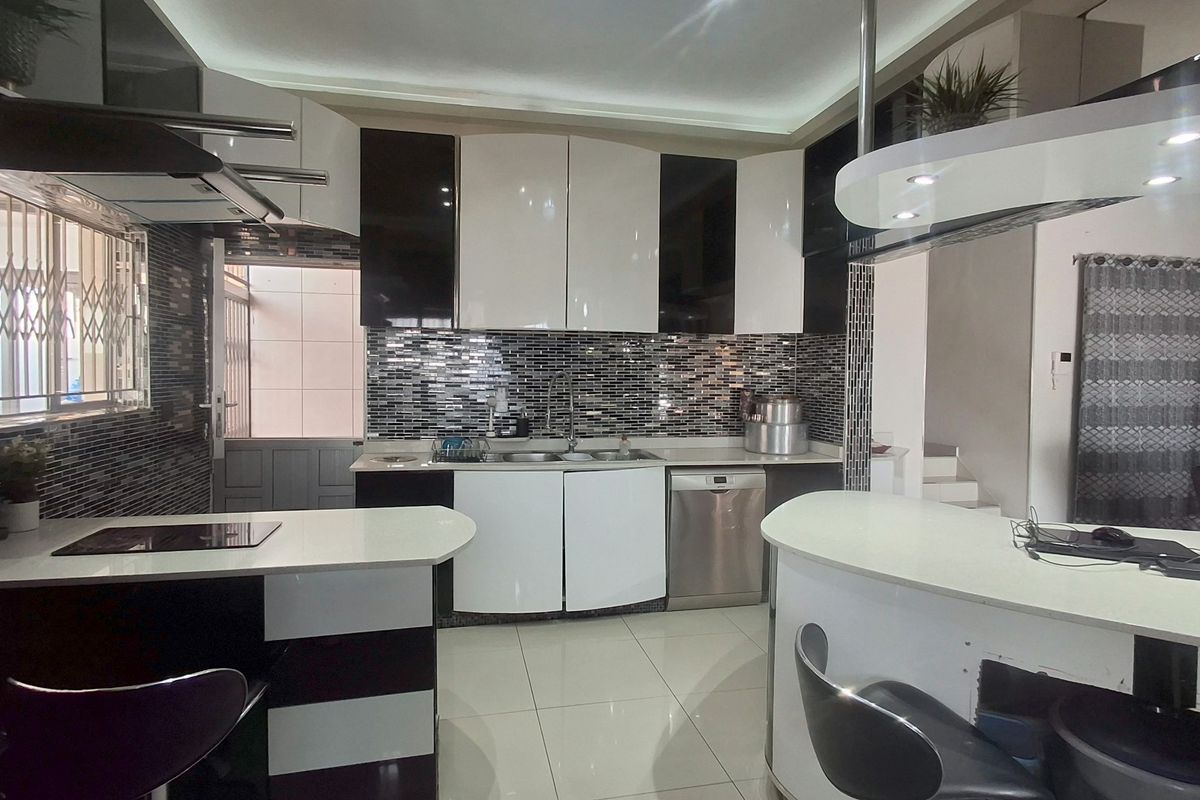 Modern kitchen featuring high-gloss cabinetry, a striking mosaic tile backsplash, integrated appliances, and a functional breakfast bar with recessed lighting.
