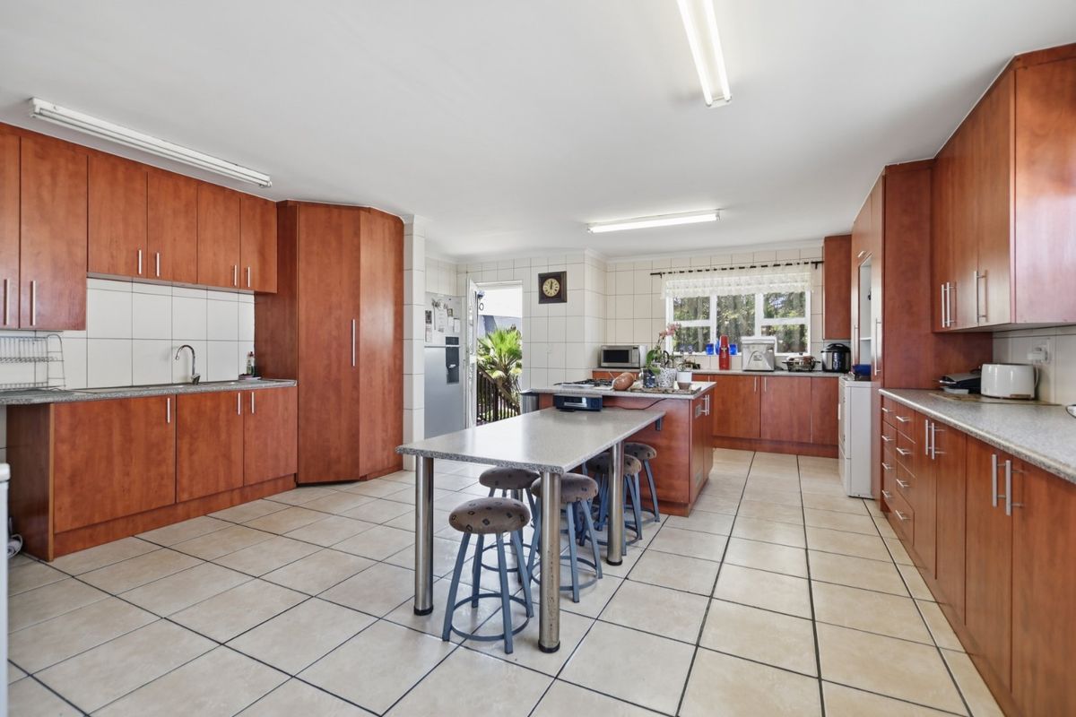 Spacious kitchen featuring extensive wood-look cabinetry, granite countertops, tiled flooring, and a central island with integrated seating area.