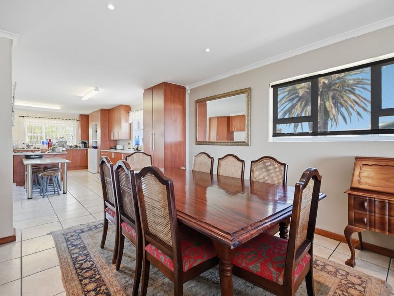 Spacious open-plan dining and kitchen area featuring tiled flooring, recessed lighting, and functional wooden cabinetry, offering a versatile layout for family living.