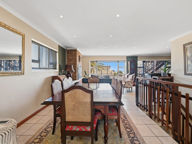 Spacious open-plan living and dining area featuring tiled floors, a brick fireplace, and large sliding doors leading to an outdoor balcony.