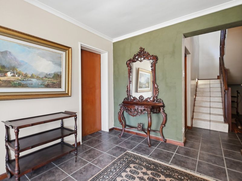 A welcoming entrance hall featuring tiled flooring and a staircase leading to the upper level, with a distinct olive-toned accent wall.