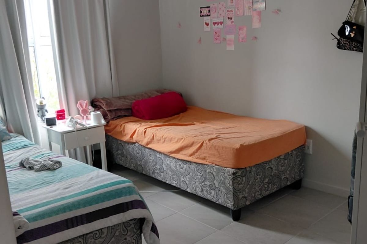 A functional bedroom featuring neutral wall tones and tiled flooring, providing a clean and simple space suitable for various bedroom configurations.