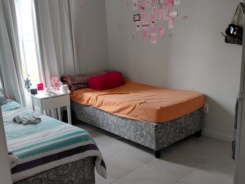 A functional bedroom featuring neutral wall tones and tiled flooring, providing a clean and simple space suitable for various bedroom configurations.
