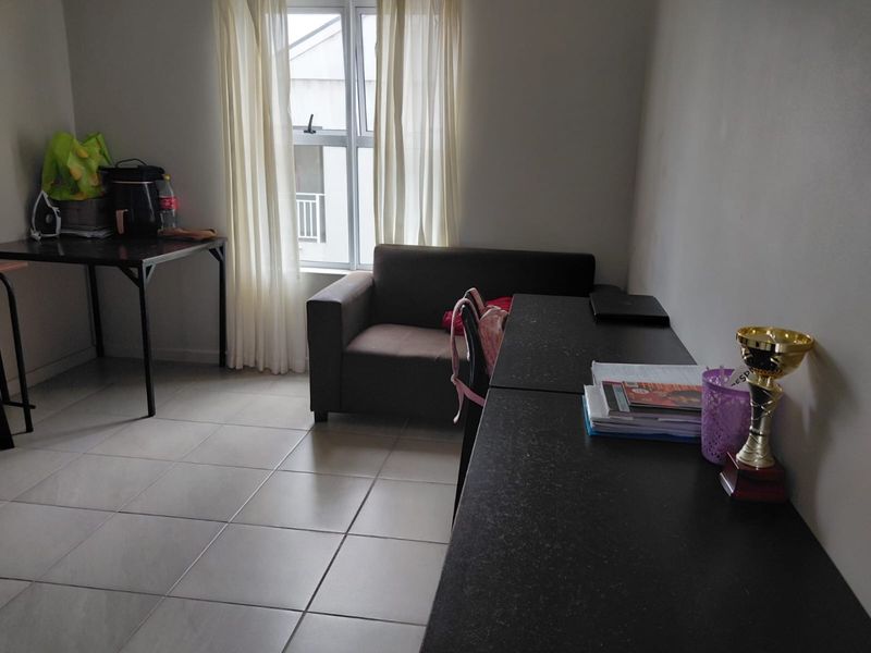 A functional living area featuring neutral tiled flooring and a large window, providing a blank canvas for interior design updates.