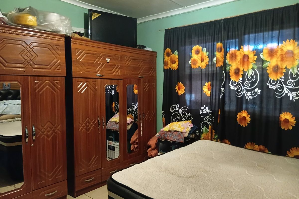 A bedroom featuring tiled flooring and coved ceilings, currently requiring cosmetic updates to the wall and ceiling finishes.