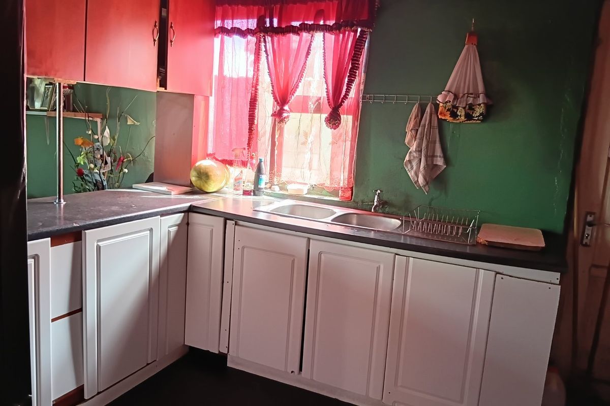 A functional kitchen featuring white built-in cabinetry, dark laminate countertops, and a double bowl sink with a window view.