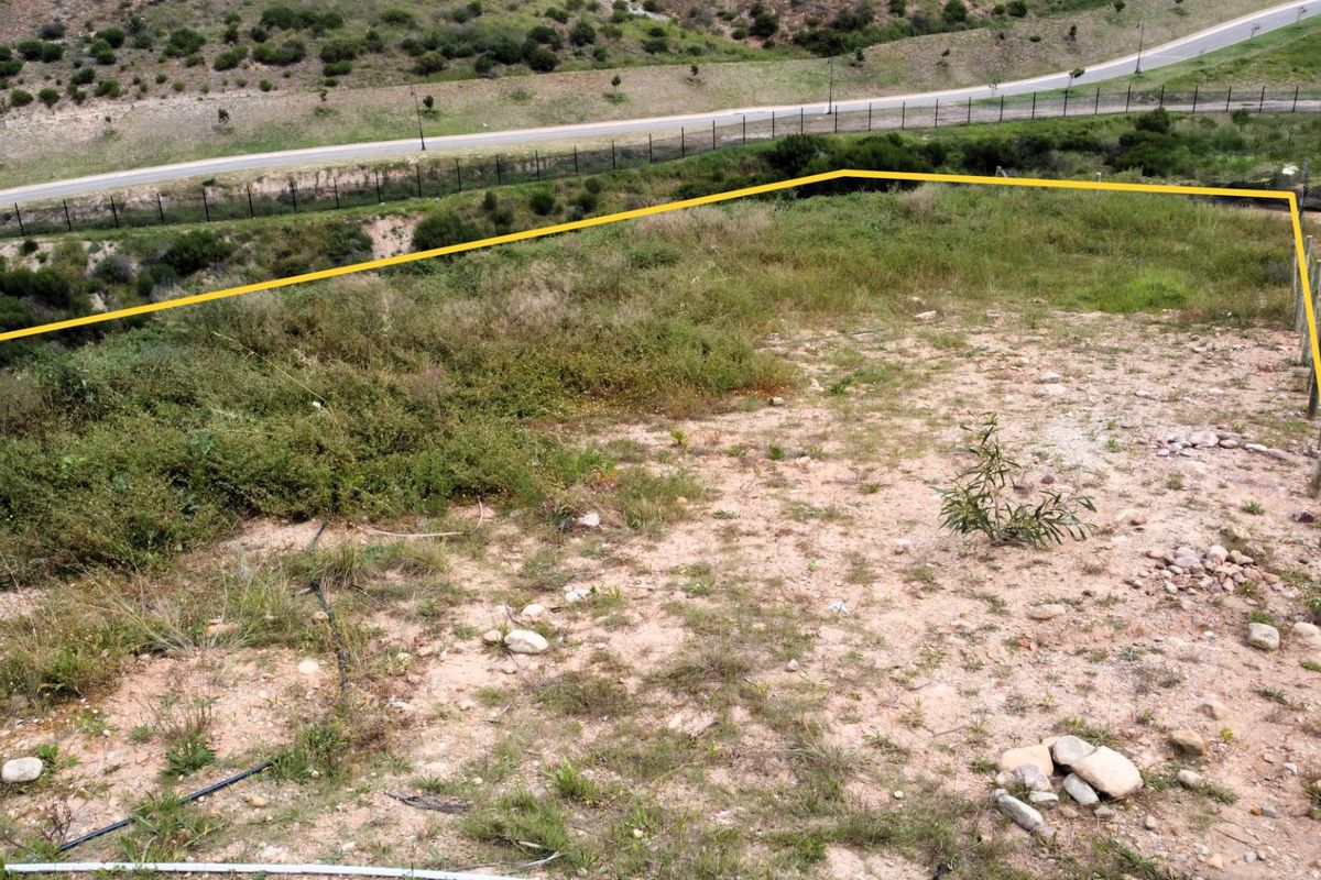 An aerial view of a vacant residential plot featuring perimeter fencing and natural vegetation, ready for development.