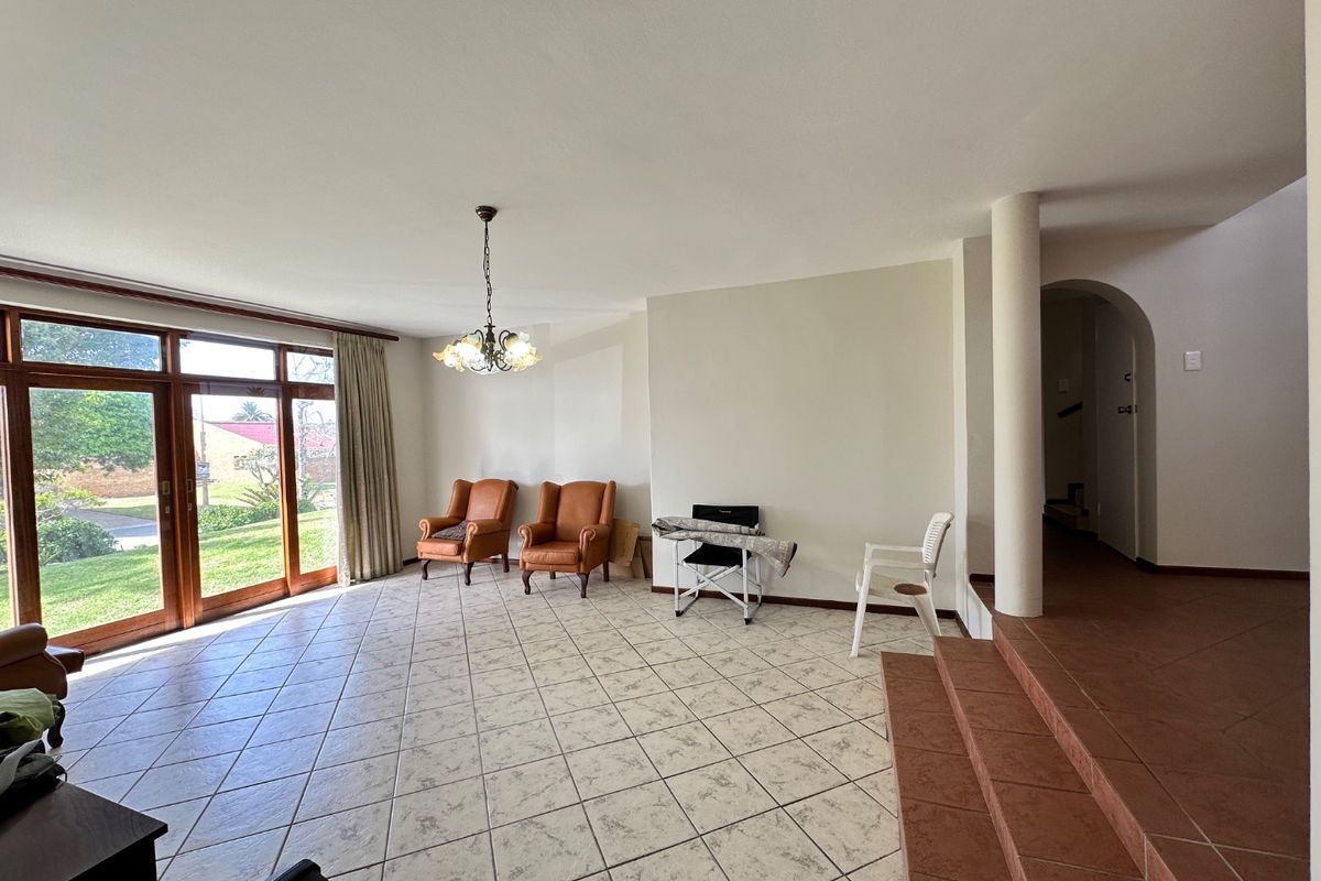 Spacious living area featuring tiled flooring, large sliding glass doors providing natural light, and a raised platform area with an arched entryway.