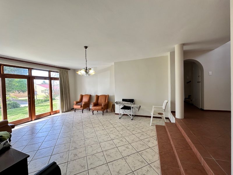 Spacious living area featuring tiled flooring, large sliding glass doors providing natural light, and a raised platform area with an arched entryway.
