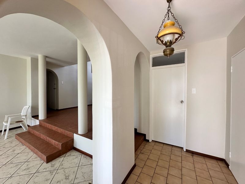 Spacious entry area featuring distinctive arched doorways, structural columns, and a stepped transition between tiled floor levels.