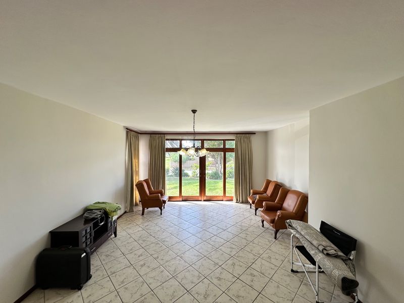 Spacious living room featuring neutral tiled flooring and large sliding glass doors that provide direct access to the garden.