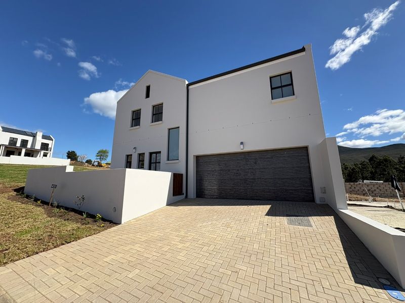 Modern double-story residential home featuring a clean plastered facade, paved driveway, and integrated double garage.