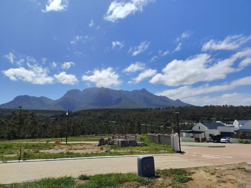 A scenic view of the surrounding mountain range and landscape from a residential estate street.
