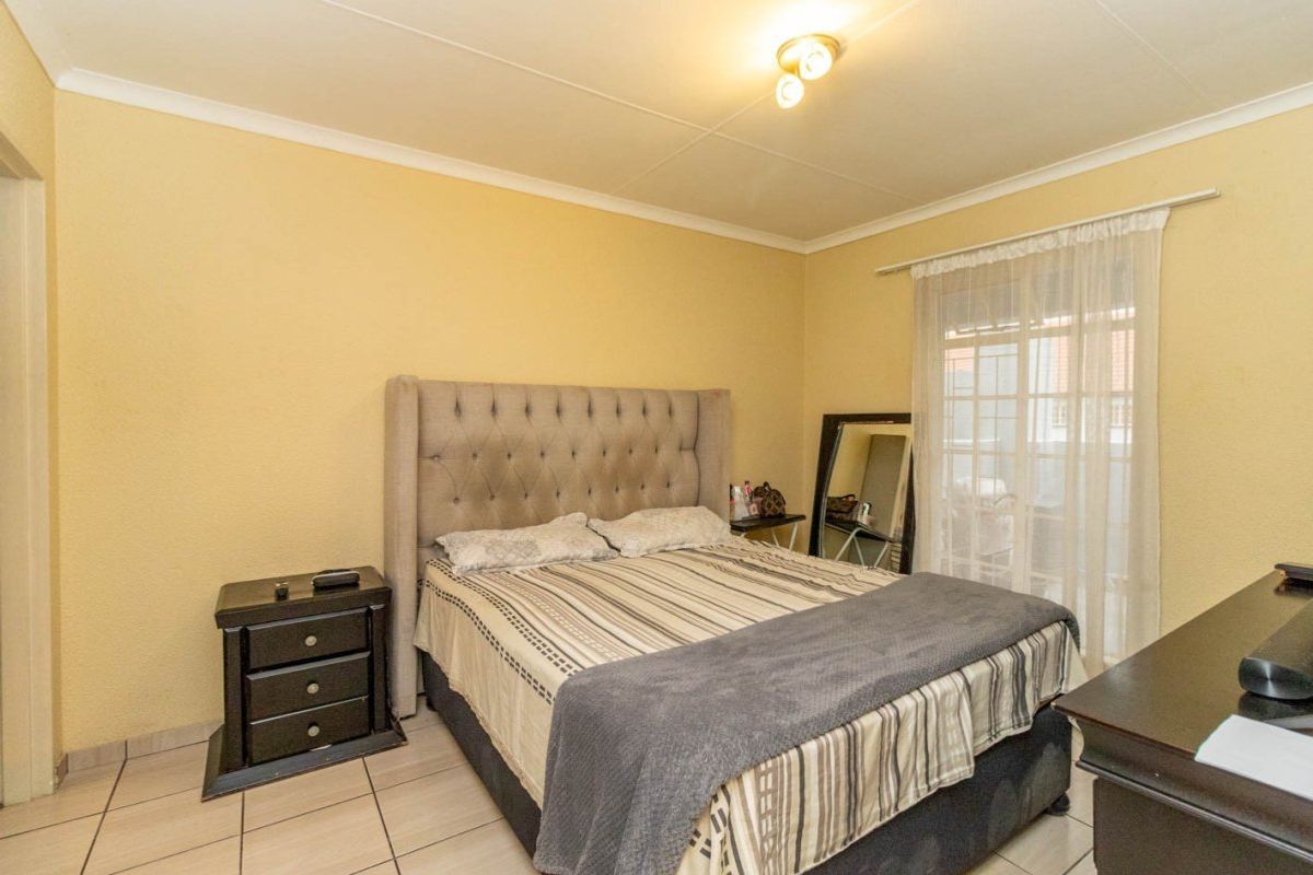 A standard bedroom featuring tiled flooring, coved ceilings, and a sliding glass door providing access to an outdoor area.