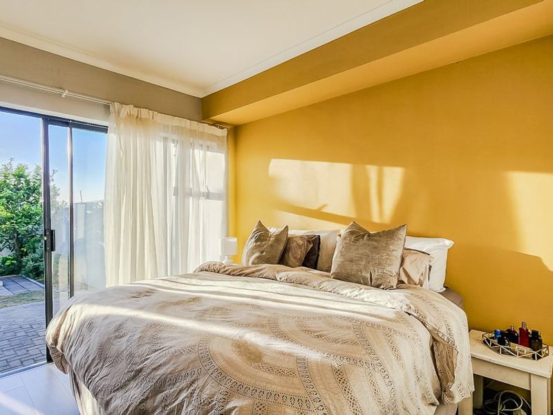 Bright bedroom featuring tiled flooring and a large sliding glass door providing direct access to the outdoor patio area.