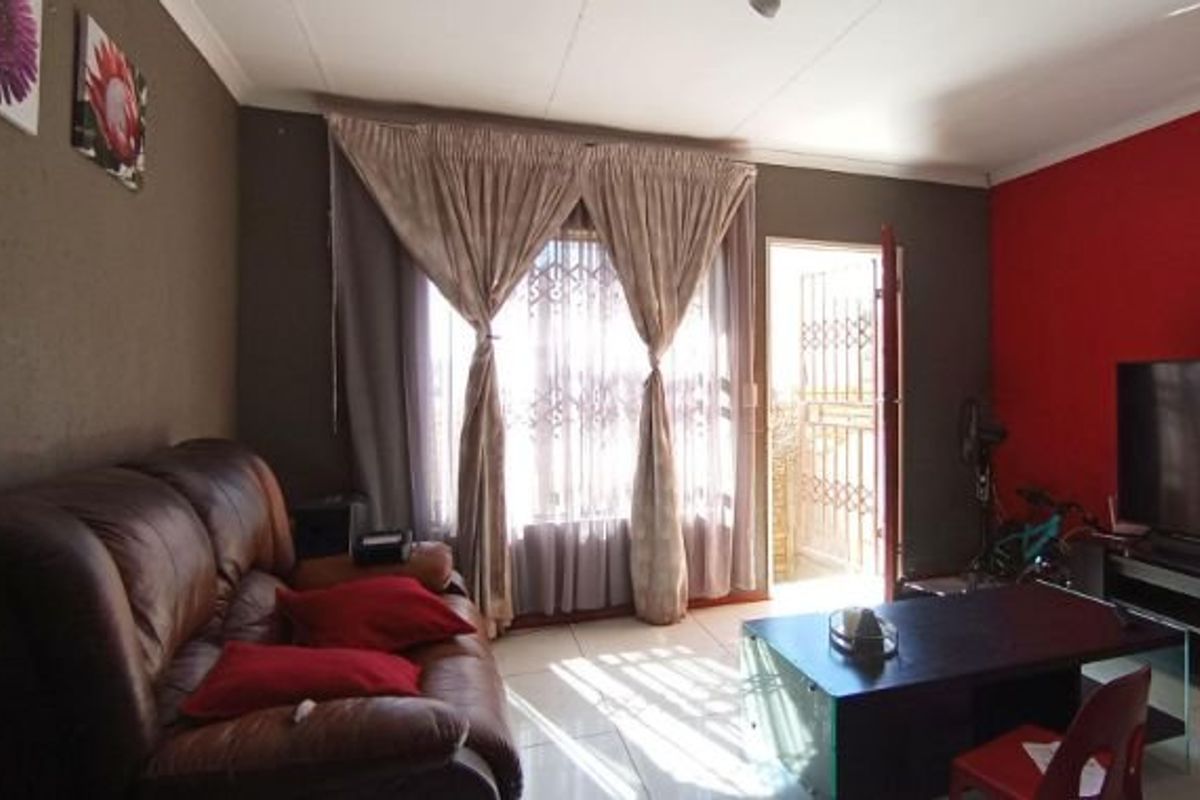 A living room featuring tiled flooring and direct access to an outdoor area through a security gate and sliding door.
