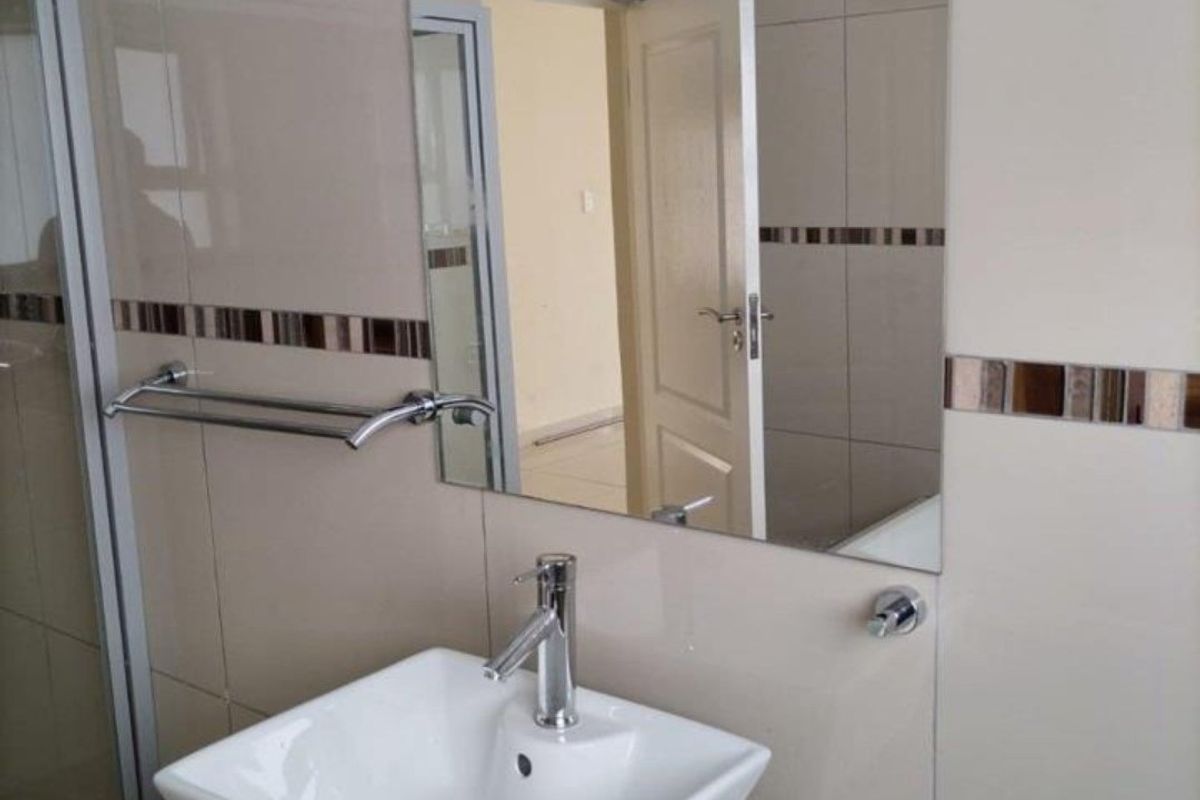 A clean, modern bathroom featuring a vessel sink on a granite vanity top, chrome fixtures, and neutral wall tiling with a decorative accent border.