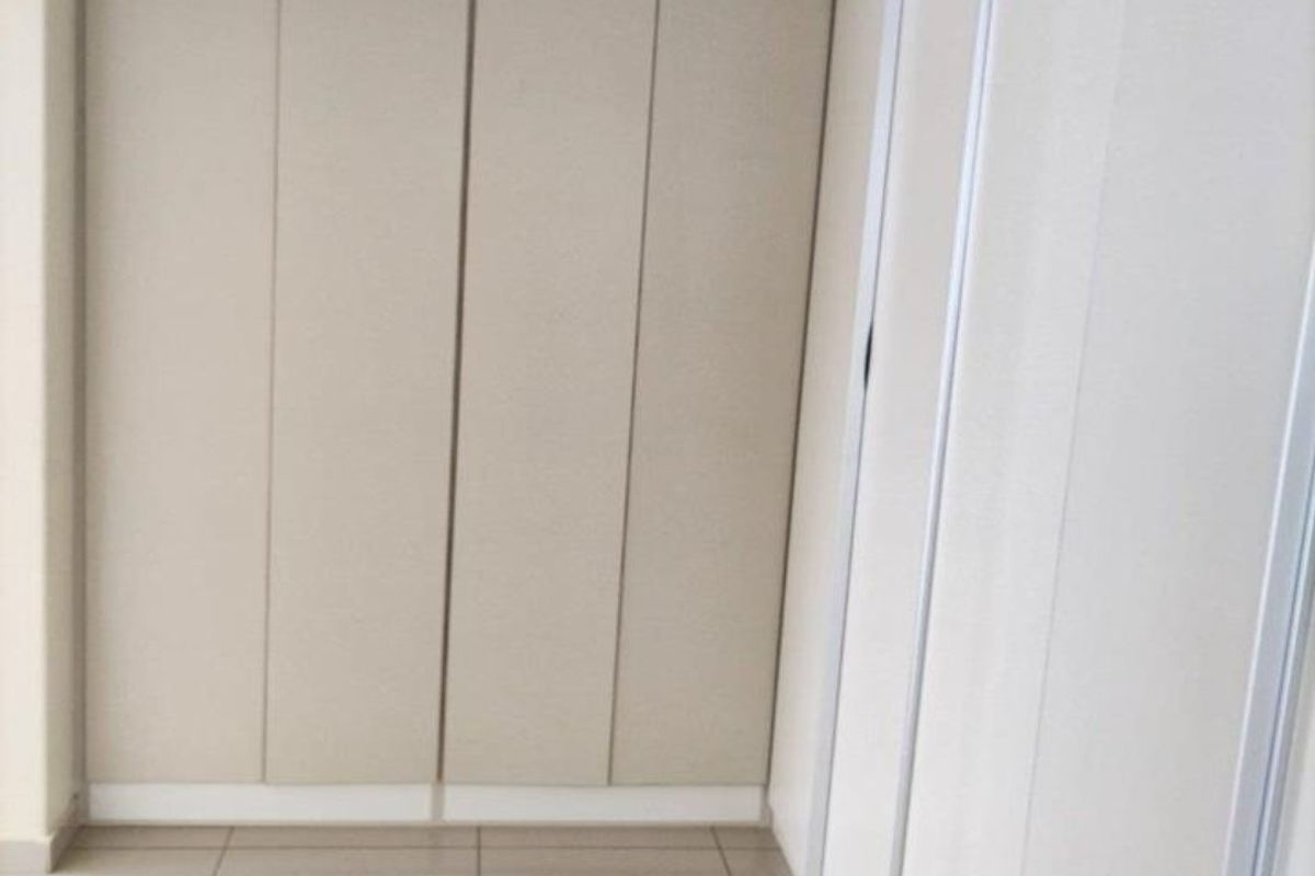 A clean, empty bedroom space featuring neutral-toned built-in cupboards and modern tiled flooring, offering a versatile canvas for interior design.