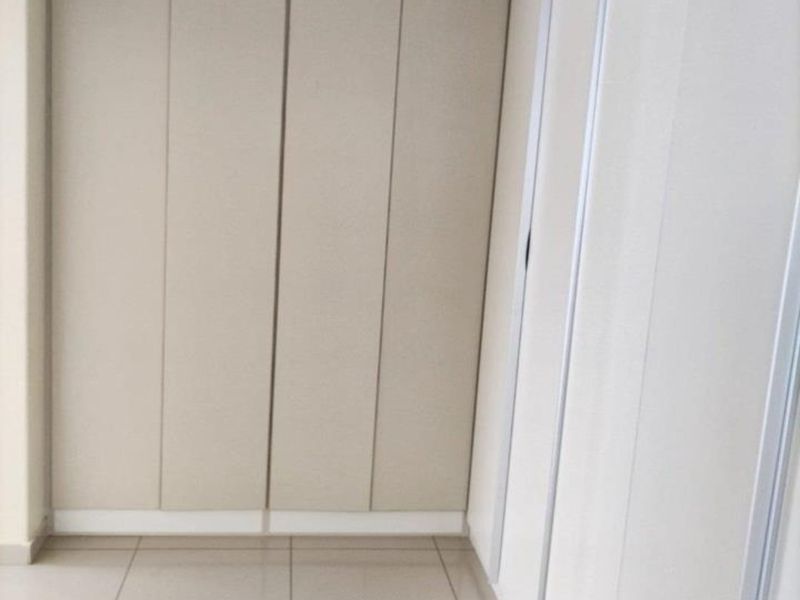 A clean, empty bedroom space featuring neutral-toned built-in cupboards and modern tiled flooring, offering a versatile canvas for interior design.
