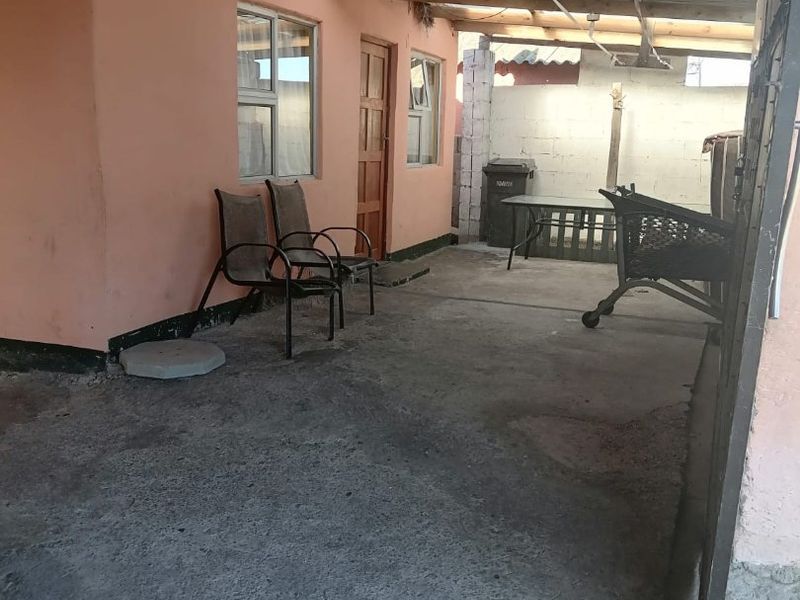 A covered outdoor patio area featuring a concrete floor and exposed timber roof structure, providing a functional space for outdoor living.