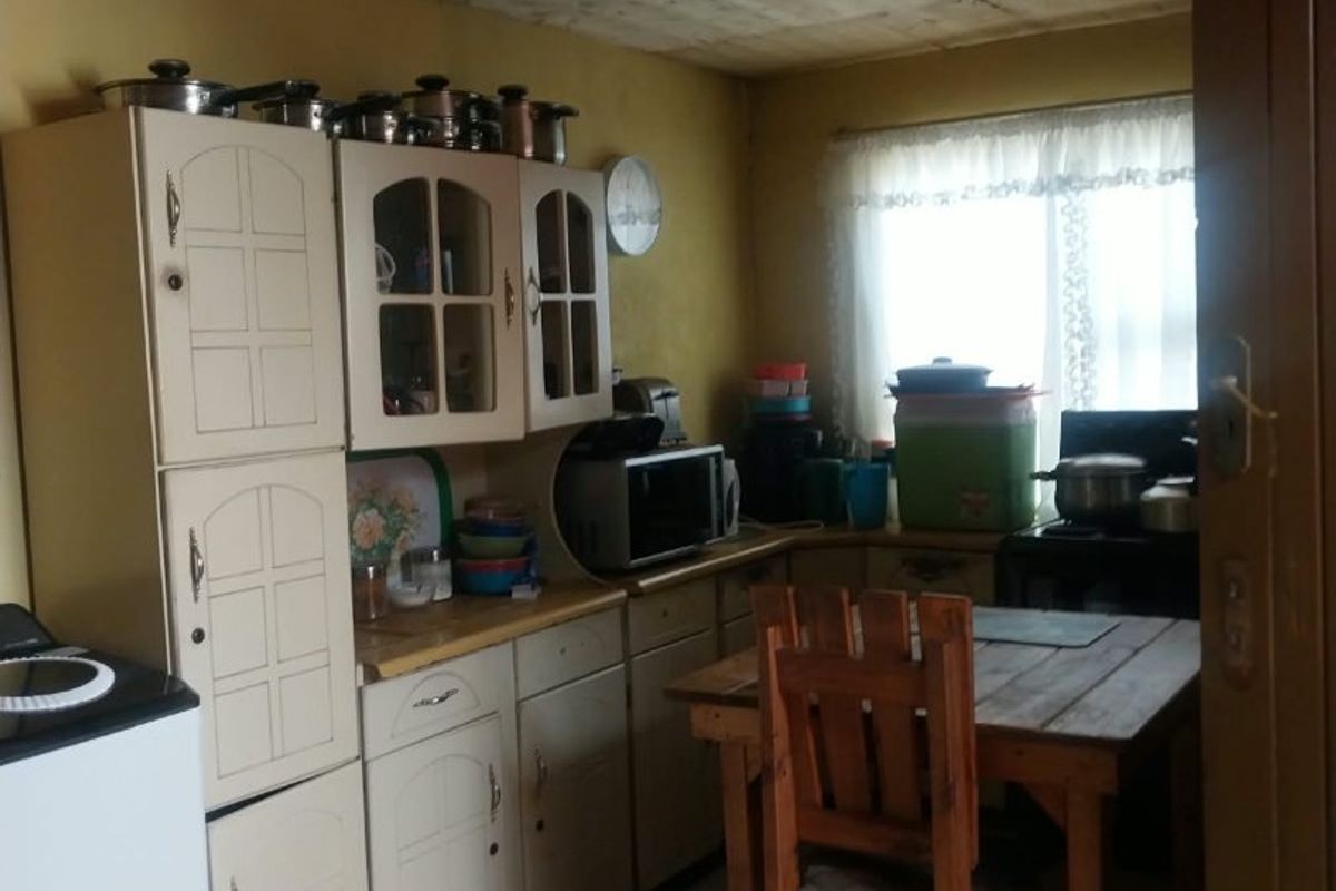 A dated kitchen featuring built-in cabinetry, tiled flooring, and a window, offering potential for modernization and cosmetic updates to improve the overall aesthetic.