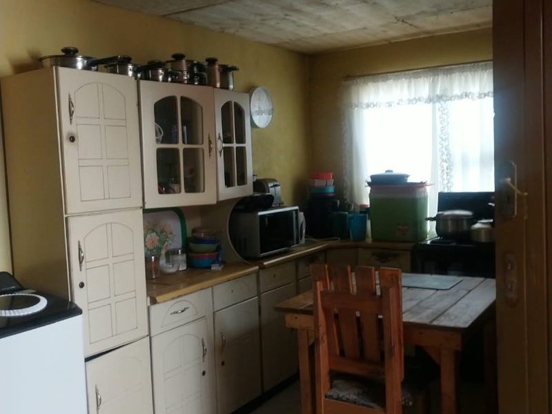 A dated kitchen featuring built-in cabinetry, tiled flooring, and a window, offering potential for modernization and cosmetic updates to improve the overall aesthetic.