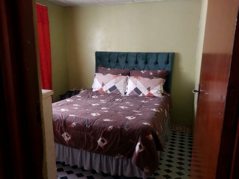 A compact bedroom featuring patterned floor tiles and a simple wall finish, offering a functional space ready for cosmetic updates.