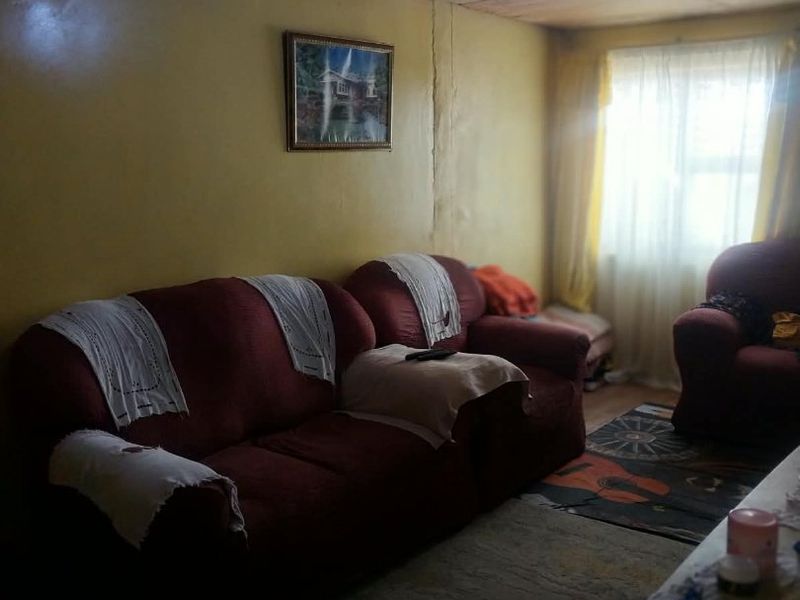 A living room featuring a timber ceiling and visible wall cracks, requiring cosmetic updates to improve the overall condition and aesthetic appeal.