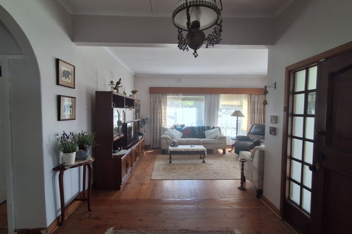 A traditional living room featuring original hardwood flooring, an elegant archway entrance, and a classic timber-framed glass door, offering a warm and character-filled space.