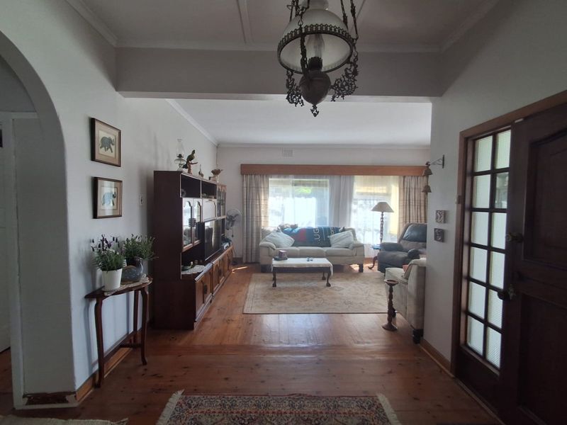 A traditional living room featuring original hardwood flooring, an elegant archway entrance, and a classic timber-framed glass door, offering a warm and character-filled space.