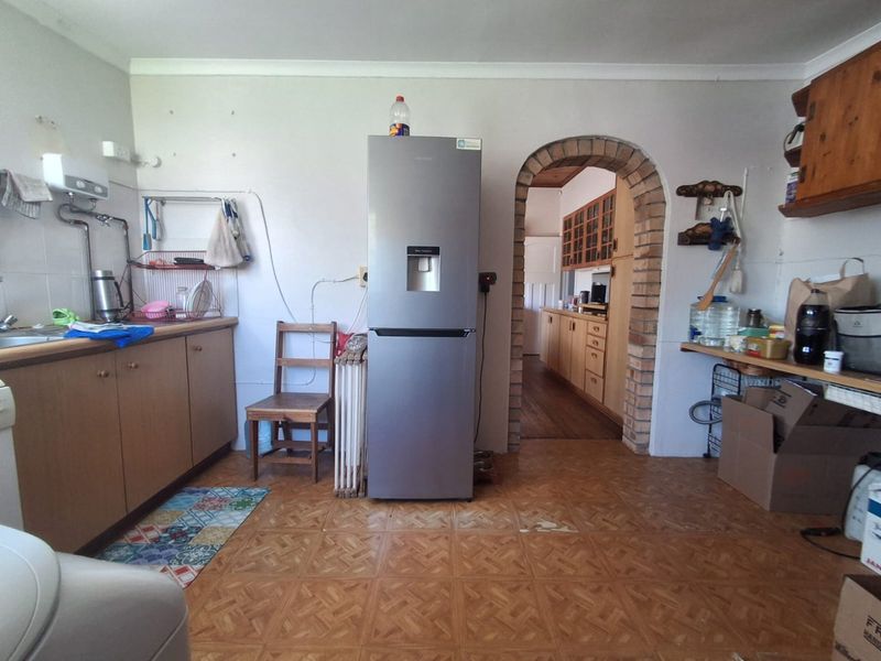 A dated kitchen featuring laminate cabinetry, a distinctive brick archway, and tiled flooring, offering potential for a modern renovation.