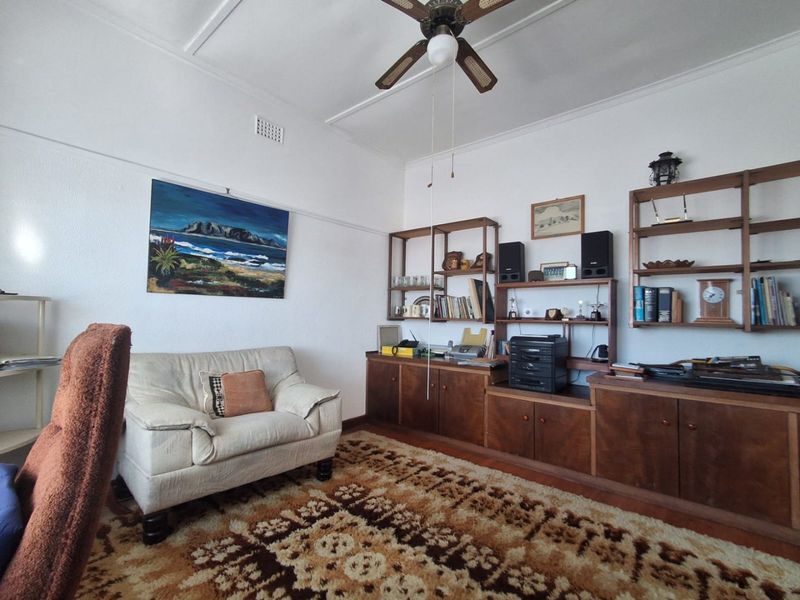 A living room featuring a ceiling fan and extensive built-in wooden cabinetry, offering a dated but functional space with classic architectural details.