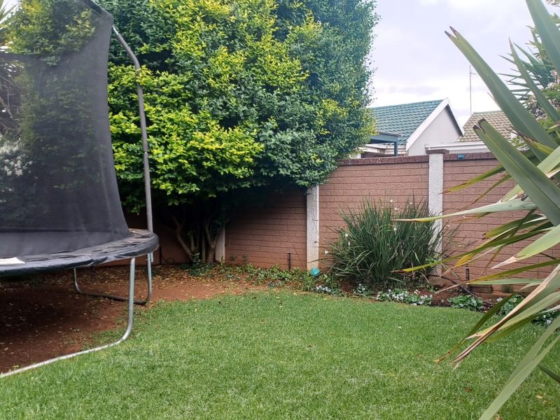 A private rear garden featuring a well-maintained lawn, established greenery, and a secure brick boundary wall.
