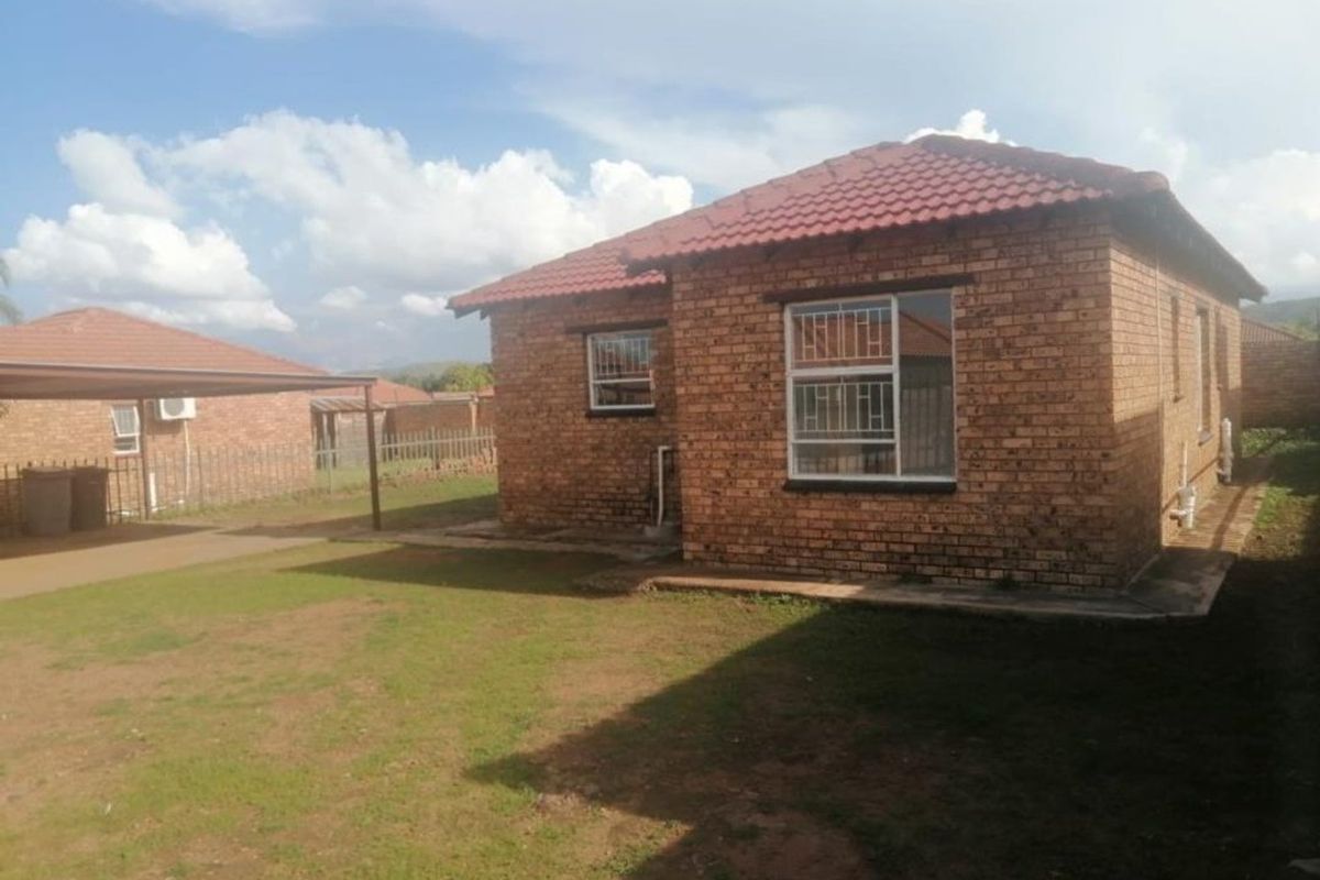 A detached face brick house featuring a tiled roof, security bars on windows, and an attached carport set within a private yard.