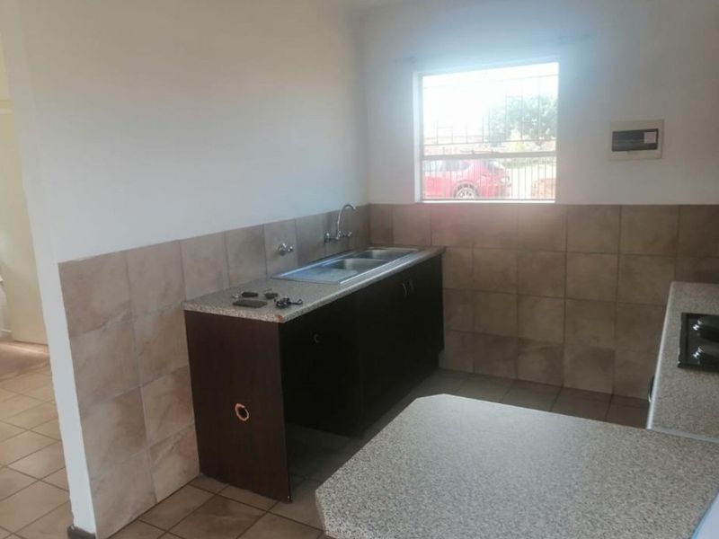 A functional kitchen space featuring tiled splashbacks, laminate countertops, and built-in cabinetry, requiring minor repairs and cosmetic updates to enhance its appeal.