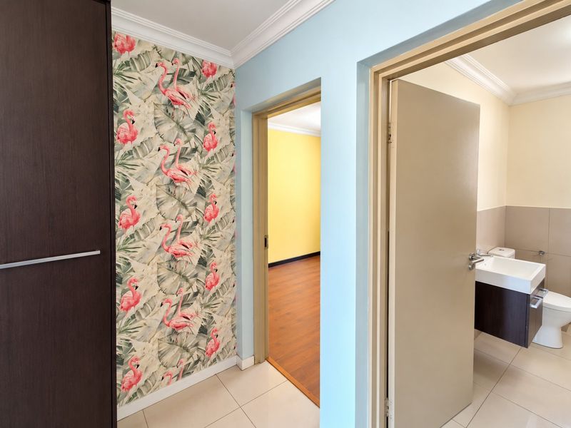 A bright hallway featuring tiled flooring, crown molding, and a built-in cupboard, providing access to a bathroom and an adjacent room.