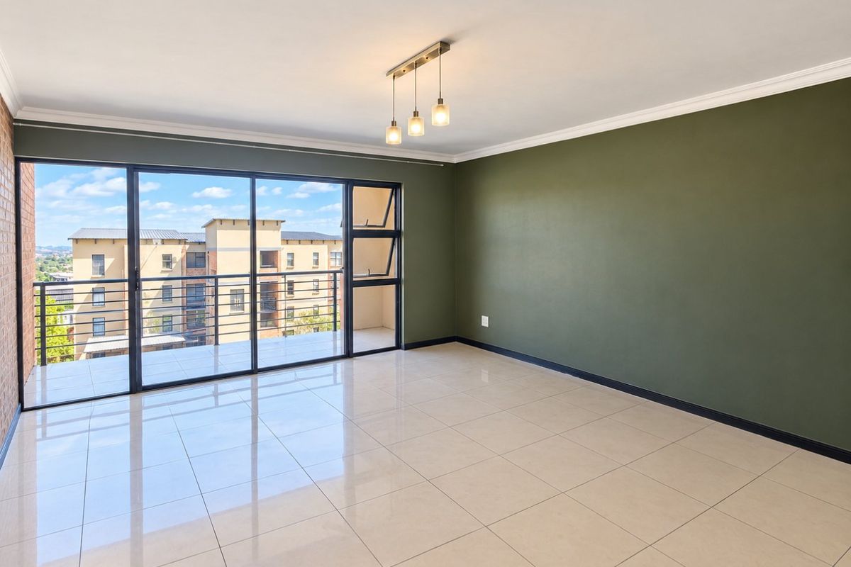 Spacious, empty living area featuring large sliding glass doors leading to a balcony, tiled flooring, and a modern ceiling light fixture.