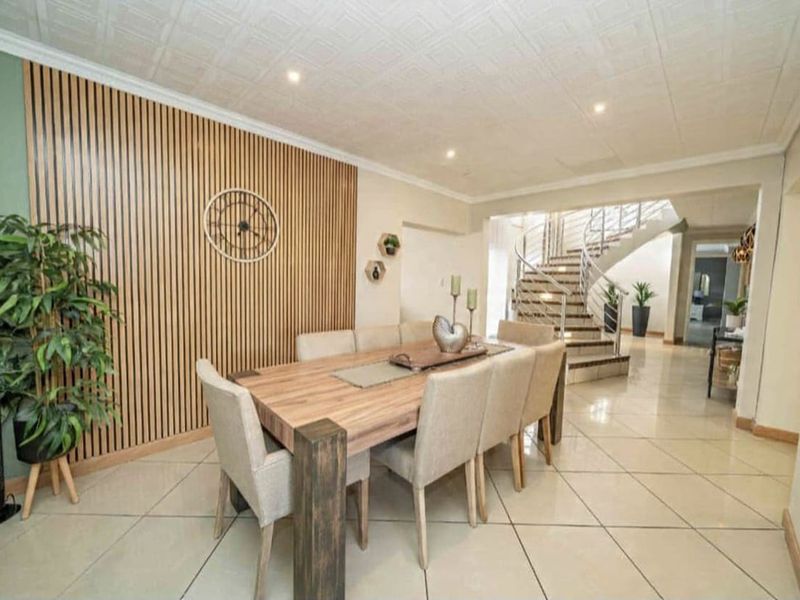 Elegant dining area featuring modern slatted timber wall paneling, polished floor tiles, and a striking curved staircase with a contemporary metal balustrade.