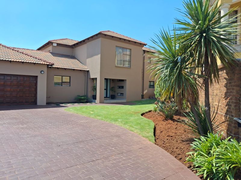 A well-maintained double-story residential property featuring a paved driveway, integrated garage, and landscaped front garden area.