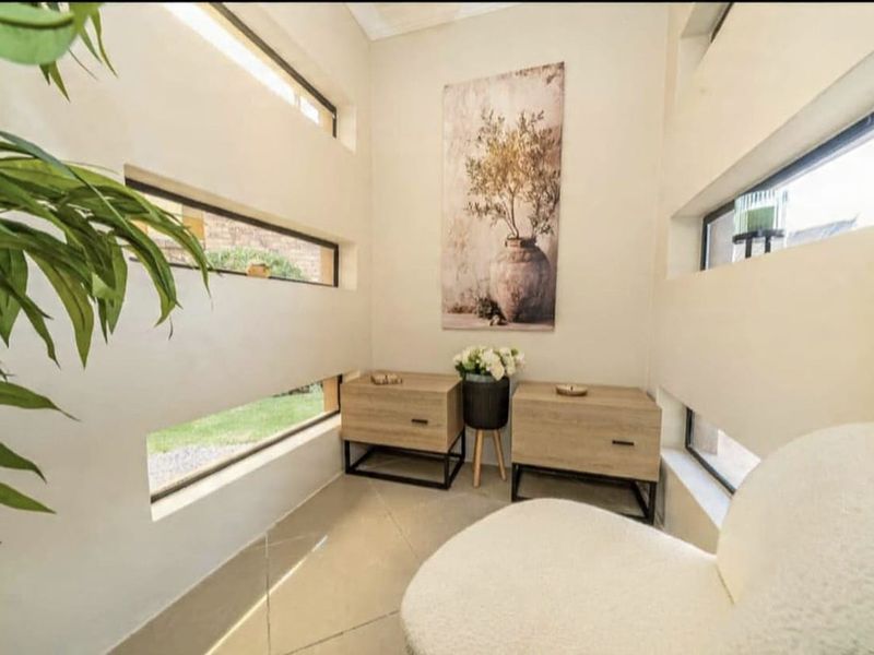 A bright, modern living space featuring unique horizontal windows that provide natural light and garden views, complemented by neutral tiled flooring.