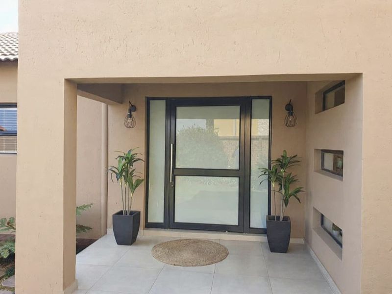 A welcoming covered entrance featuring a modern frosted glass front door, tiled porch flooring, and decorative recessed wall niches.