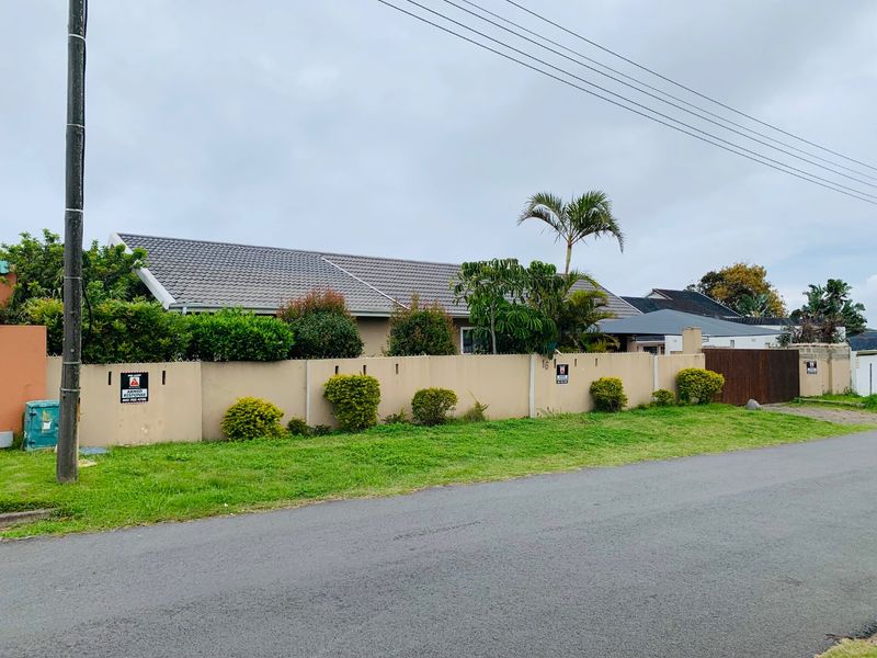 Front view of the property featuring a perimeter wall, tiled roof, and gated driveway access from the street.